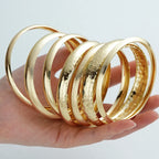 Lot de 7 joncs empilables ouverts, martelés et lisses, en or